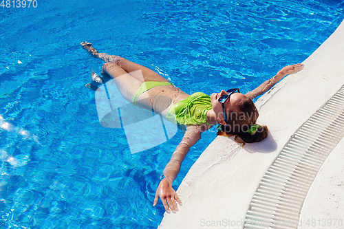 Image of teen girl relaxing near swimming pool