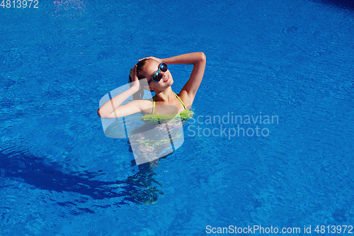 Image of teen girl relaxing near swimming pool