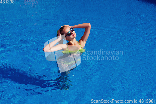 Image of teen girl relaxing near swimming pool