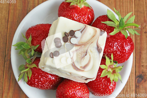 Image of ripe red strawberries on the white plate and cake