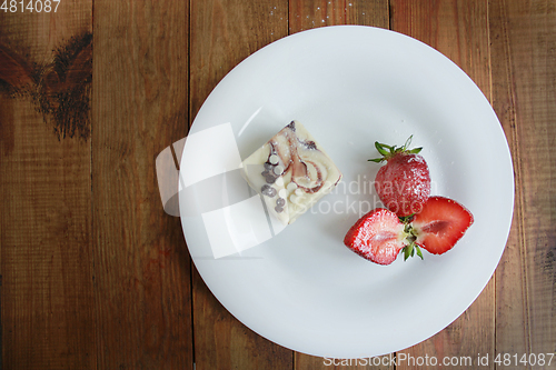 Image of cut strawberries on the white plate and cake