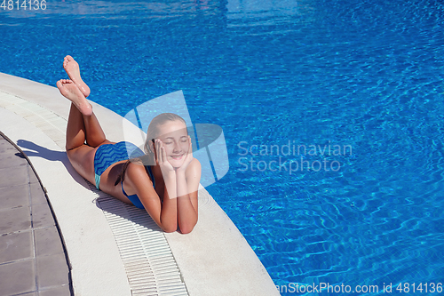 Image of teen girl relaxing near swimming pool