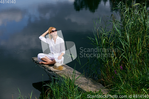 Image of Young woman resting near lake