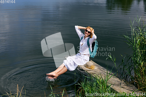 Image of Young woman resting near lake