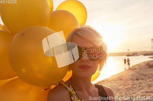 Image of Young woman with many golden balloons.