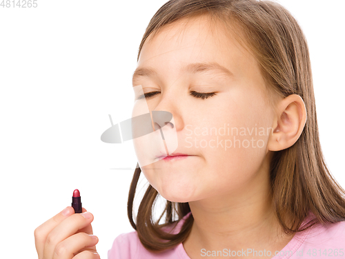 Image of Little girl is applying lipstick