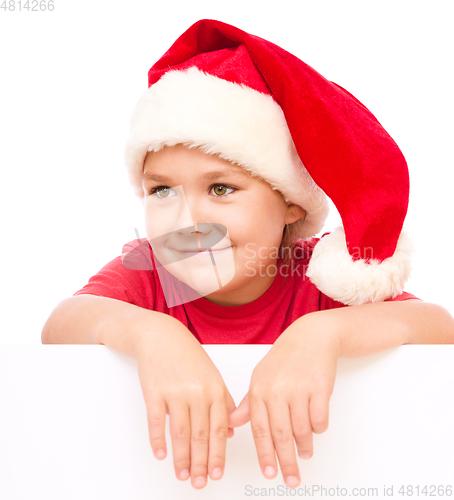 Image of Little girl in santa hat is holding blank board