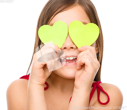 Image of Little girl is holding hearts over her eyes
