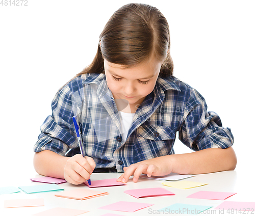 Image of Girl is writing on color stickers using pen