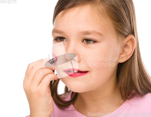 Image of Little girl is applying lipstick on her cheek