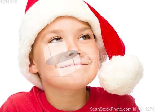 Image of Little girl in santa hat is daydreaming