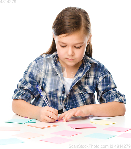 Image of Girl is writing on color stickers using pen