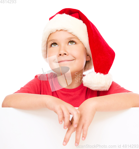 Image of Little girl in santa hat is holding blank board