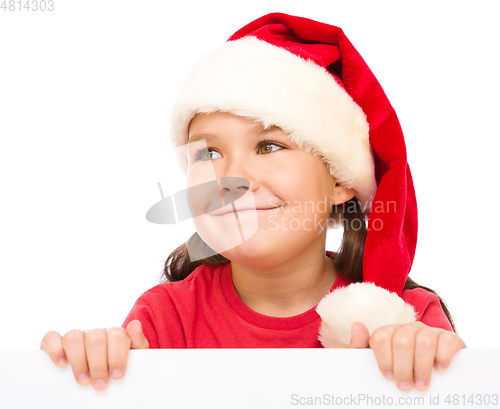 Image of Little girl in santa hat is holding blank board