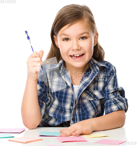 Image of Girl is writing on color stickers using pen