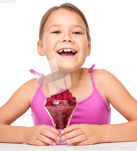 Image of Happy little girl is eating raspberries