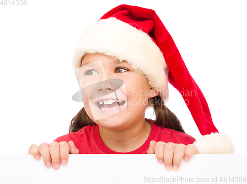 Image of Little girl in santa hat is holding blank board