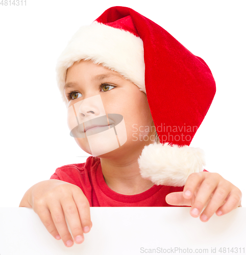 Image of Little girl in santa hat is holding blank board