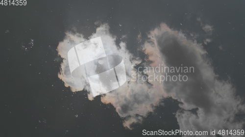 Image of Clouds and sun reflected in the lake water.