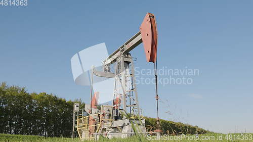 Image of Operating oil and gas well in oil field, profiled against the blue sky