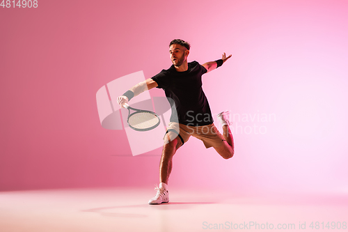 Image of Young caucasian man playing tennis isolated on pink studio background, action and motion concept
