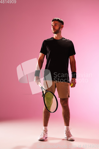 Image of Young caucasian man playing tennis isolated on pink studio background, action and motion concept