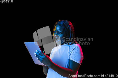 Image of African young woman\'s portrait on dark studio background in neon. Concept of human emotions, facial expression, youth, sales, ad.
