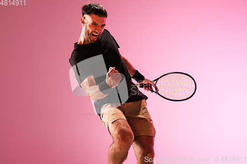 Image of Young caucasian man playing tennis isolated on pink studio background, action and motion concept