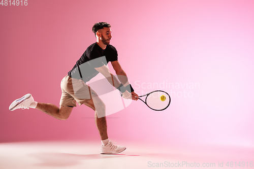 Image of Young caucasian man playing tennis isolated on pink studio background, action and motion concept