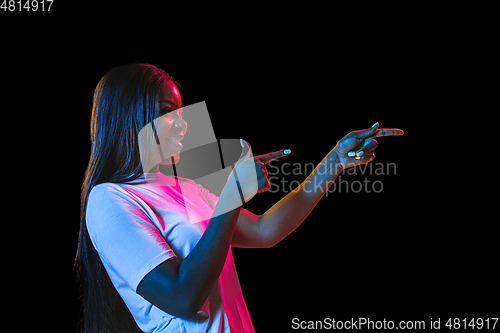Image of African young woman\'s portrait on dark studio background in neon. Concept of human emotions, facial expression, youth, sales, ad.