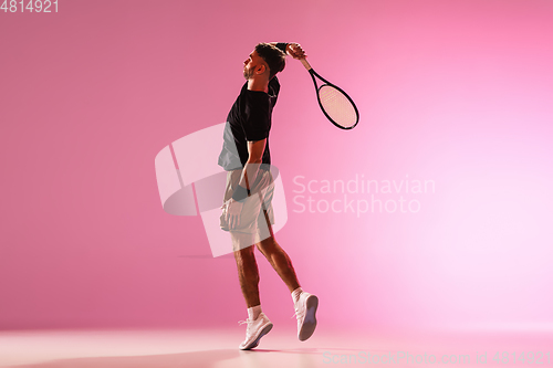Image of Young caucasian man playing tennis isolated on pink studio background, action and motion concept