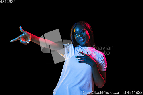 Image of African young woman\'s portrait on dark studio background in neon. Concept of human emotions, facial expression, youth, sales, ad.