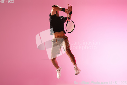 Image of Young caucasian man playing tennis isolated on pink studio background, action and motion concept