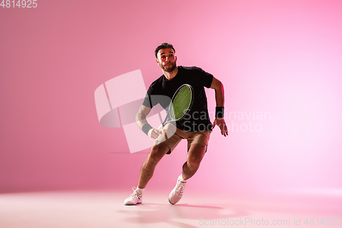 Image of Young caucasian man playing tennis isolated on pink studio background, action and motion concept
