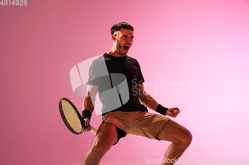 Image of Young caucasian man playing tennis isolated on pink studio background, action and motion concept