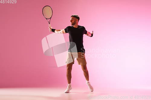 Image of Young caucasian man playing tennis isolated on pink studio background, action and motion concept