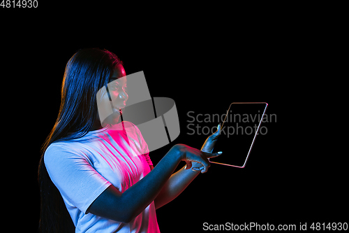 Image of African young woman\'s portrait on dark studio background in neon. Concept of human emotions, facial expression, youth, sales, ad.