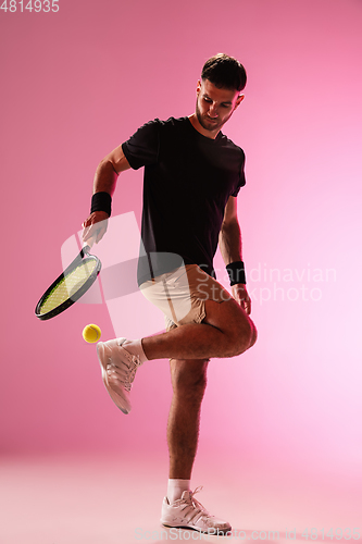 Image of Young caucasian man playing tennis isolated on pink studio background, action and motion concept