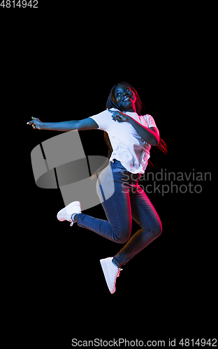 Image of African young woman\'s portrait on dark studio background in neon. Concept of human emotions, facial expression, youth, sales, ad.