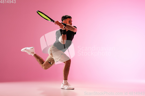 Image of Young caucasian man playing tennis isolated on pink studio background, action and motion concept