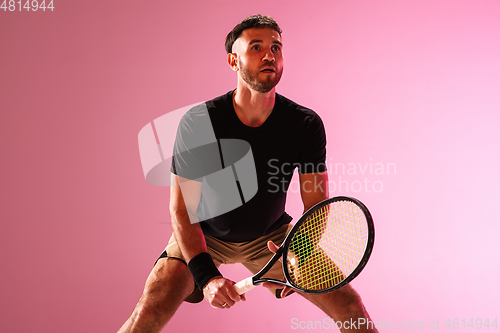 Image of Young caucasian man playing tennis isolated on pink studio background, action and motion concept