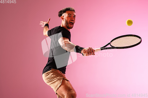 Image of Young caucasian man playing tennis isolated on pink studio background, action and motion concept