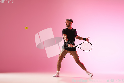 Image of Young caucasian man playing tennis isolated on pink studio background, action and motion concept