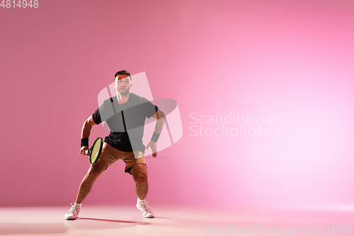 Image of Young caucasian man playing tennis isolated on pink studio background, action and motion concept