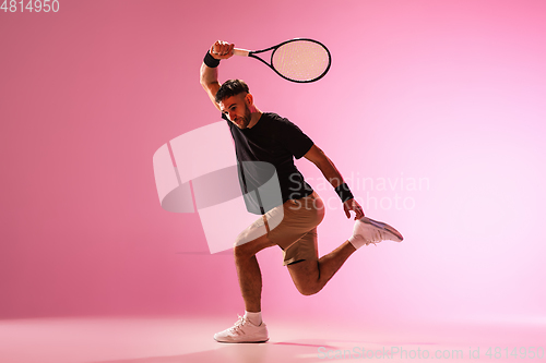 Image of Young caucasian man playing tennis isolated on pink studio background, action and motion concept