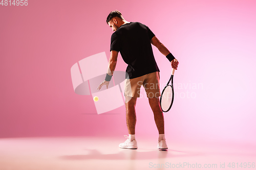 Image of Young caucasian man playing tennis isolated on pink studio background, action and motion concept