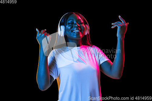 Image of African young woman\'s portrait on dark studio background in neon. Concept of human emotions, facial expression, youth, sales, ad.
