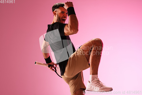Image of Young caucasian man playing tennis isolated on pink studio background, action and motion concept