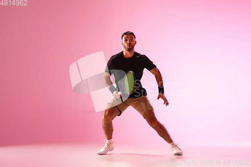Image of Young caucasian man playing tennis isolated on pink studio background, action and motion concept