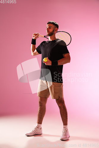 Image of Young caucasian man playing tennis isolated on pink studio background, action and motion concept